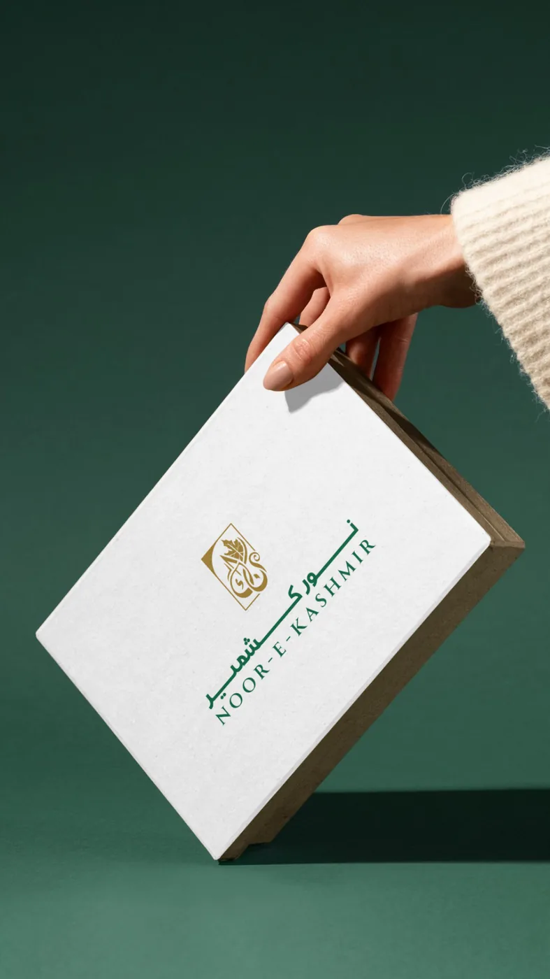 A hand holding an ivory keepsake box against deep green